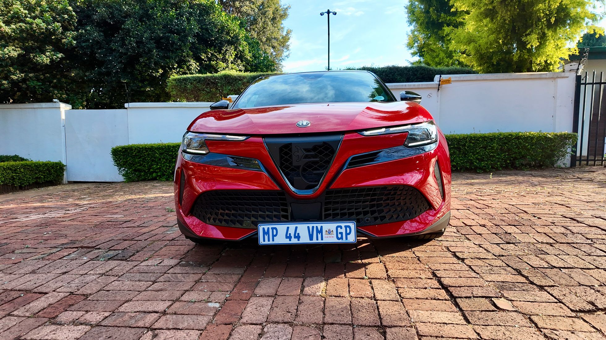 Front view of the red Alfa Romeo Junior Elettrica Veloce featuring its distinctive LED headlights and Alfa Romeo shield grille.