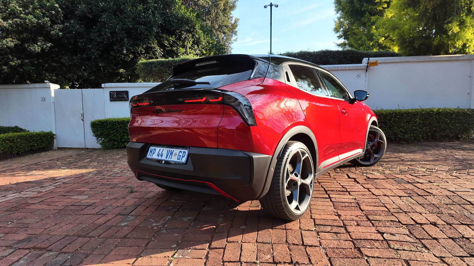 Rear three-quarter view of the Alfa Romeo Junior Elettrica Veloce featuring its black roof, LED taillights and sporty styling.