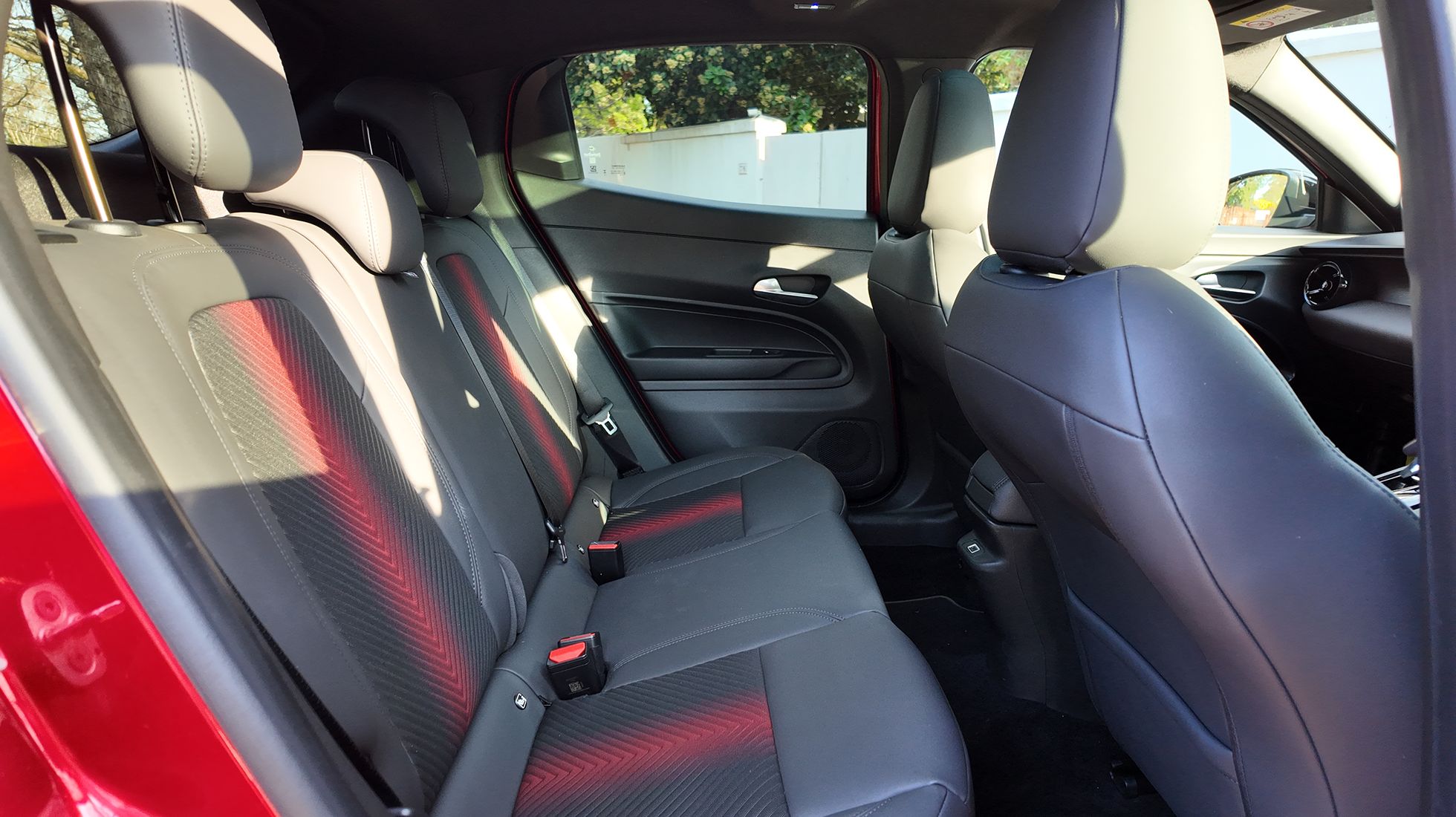 Rear passenger seats of the Alfa Romeo Junior Elettrica Veloce featuring black upholstery with distinctive red accents.