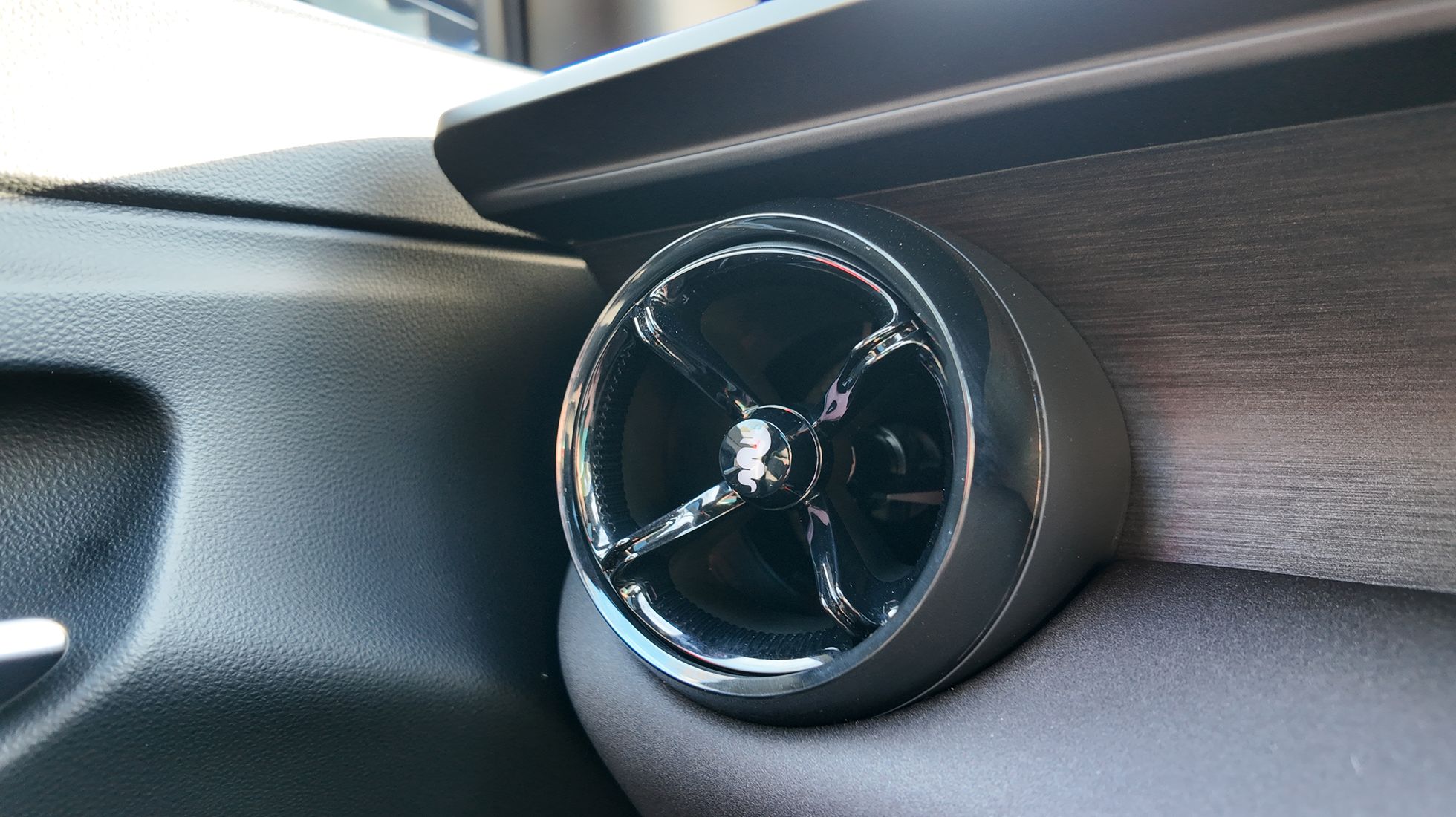 Close-up of the Alfa Romeo Junior Elettrica Veloce circular dashboard air vent featuring the brand's serpent emblem.
