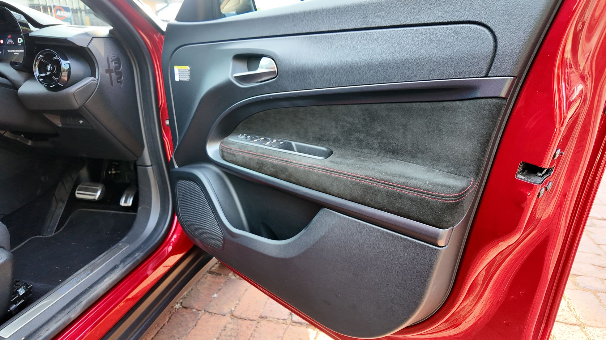 Alfa Romeo Junior Elettrica Veloce front door panel featuring soft-touch trim, red stitching and electric window controls.